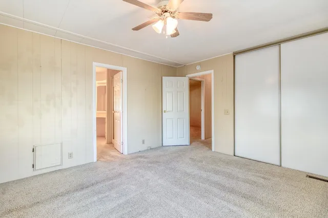 a view of an empty room and chandelier fan