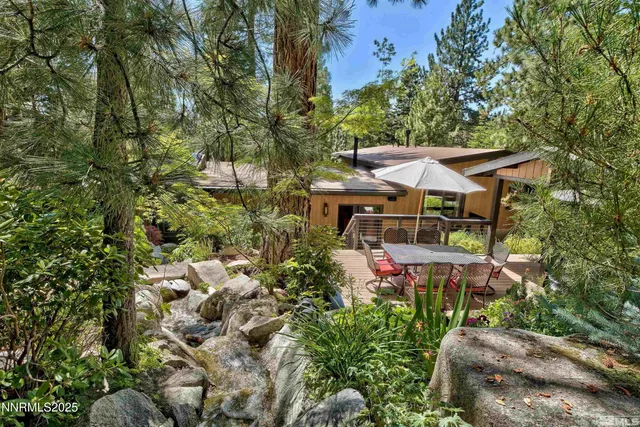 a view of house with seating space and trees in the background