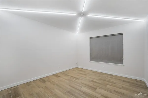 a view of an empty room with wooden floor closet and a window