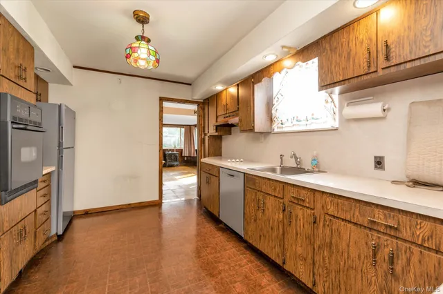 a kitchen with stainless steel appliances granite countertop a sink a stove cabinets counter space and a window