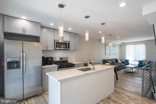 a kitchen with stainless steel appliances kitchen island granite countertop a refrigerator a sink a stove and a cabinets with wooden floor