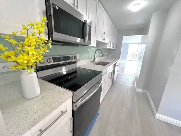 a kitchen with stainless steel appliances a sink a microwave a stove and a counter space