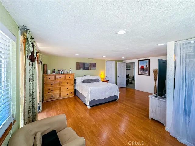 a bedroom with a bed a couch and a flat screen tv