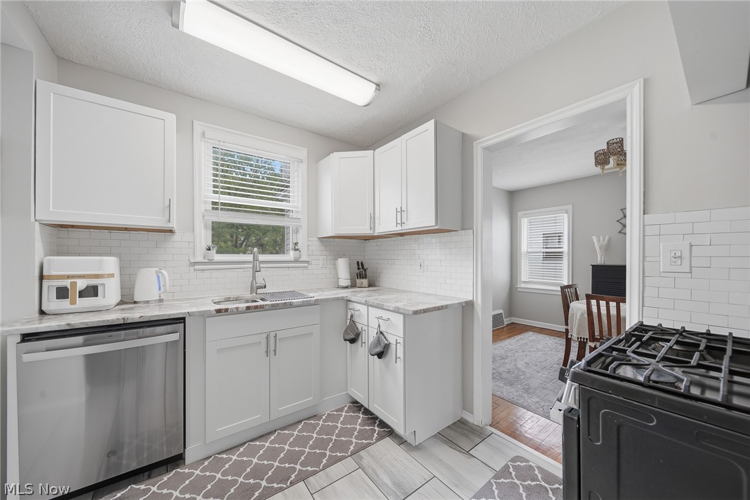2231 Brockway Road University Heights, OH 44118 - Photo 13 of 46 Kitchen featuring white shaker-style cabinetry, a white subway tile backsplash, and a stainless steel dishwasher