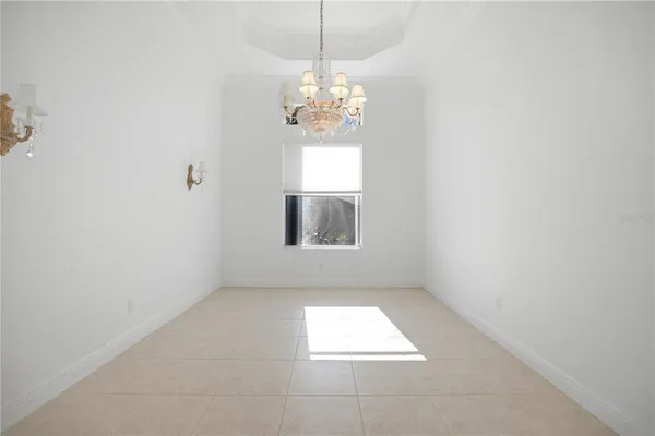 en empty room with windows and chandelier fan