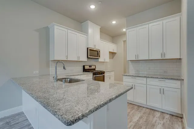 a kitchen with granite countertop a sink a stove a microwave and cabinets