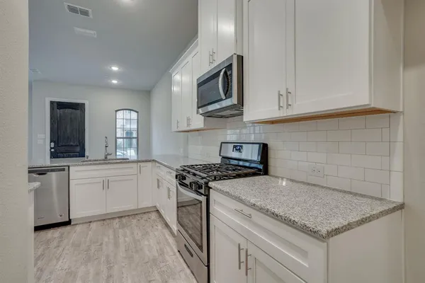 a kitchen with stainless steel appliances granite countertop a sink a stove and a microwave