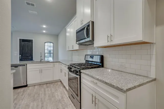 a kitchen with stainless steel appliances granite countertop a sink a stove and a microwave
