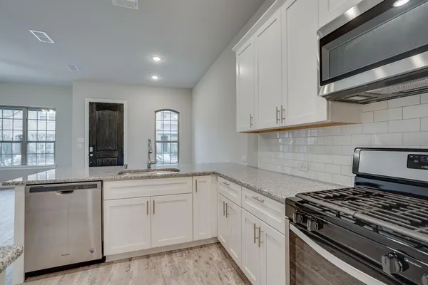 a white kitchen with granite top and stainless steel appliances