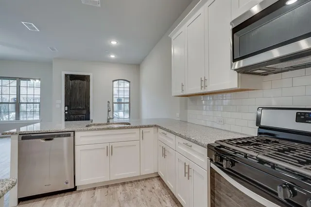 a white kitchen with granite top and stainless steel appliances