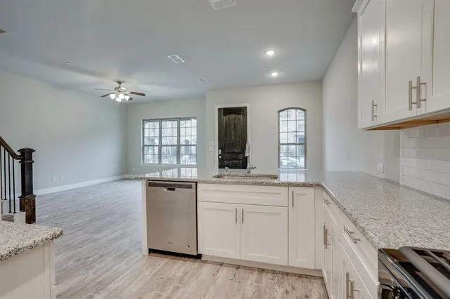 a kitchen with granite countertop a sink stainless steel appliances and cabinets