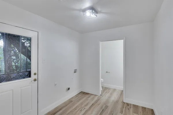 a view of an empty room with wooden floor and a window