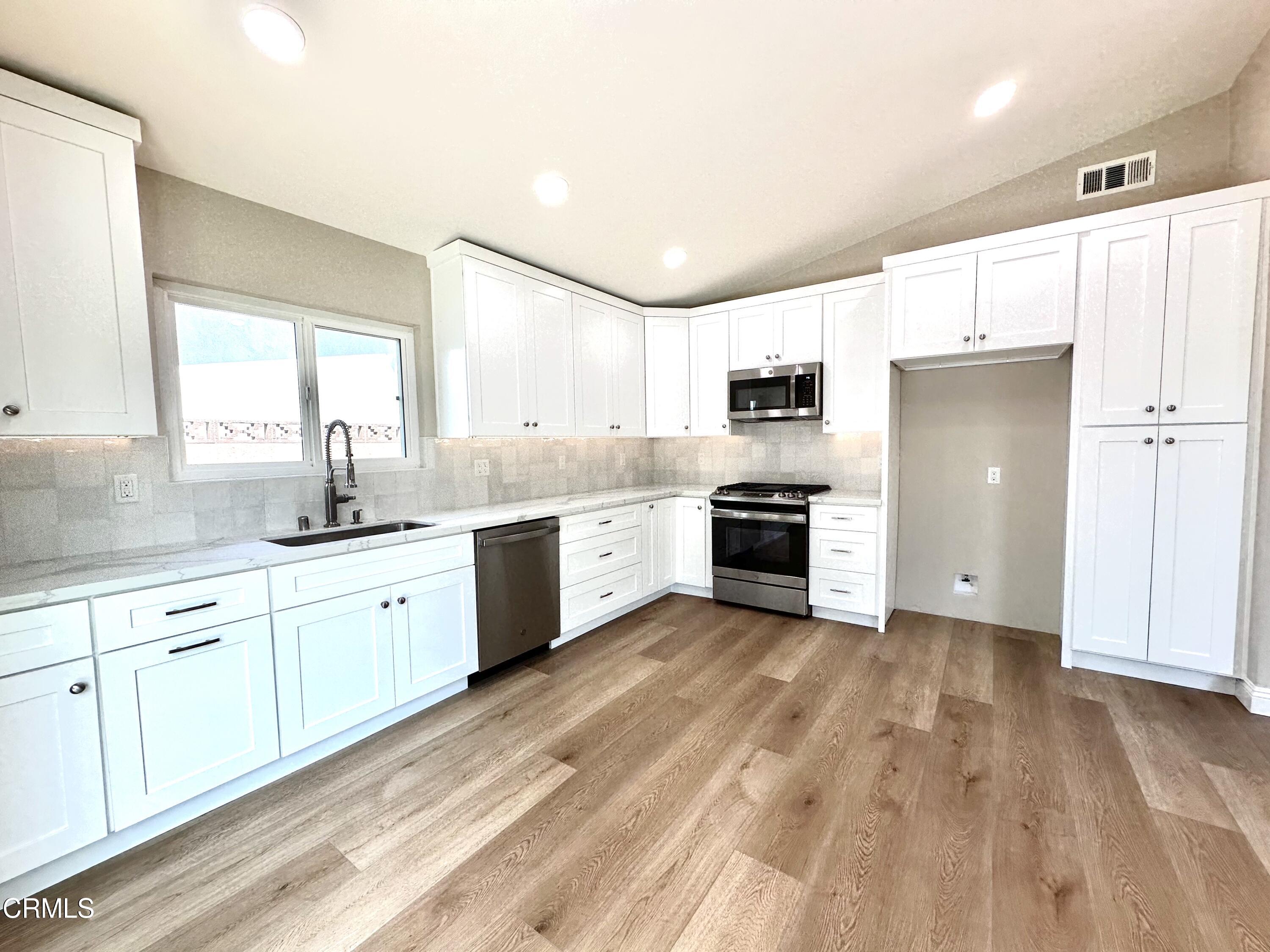 3031 Merced Place Oxnard, CA 93033 - Photo 7 of 26 a large kitchen with a sink dishwasher a stove and a refrigerator with wooden floor