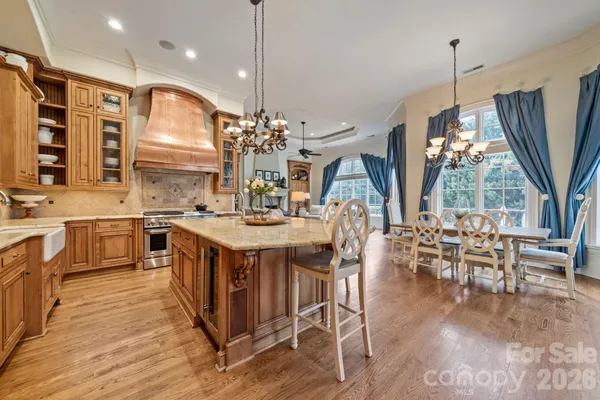 a kitchen with stainless steel appliances granite countertop a stove a sink a oven a dining table and chairs with wooden floor