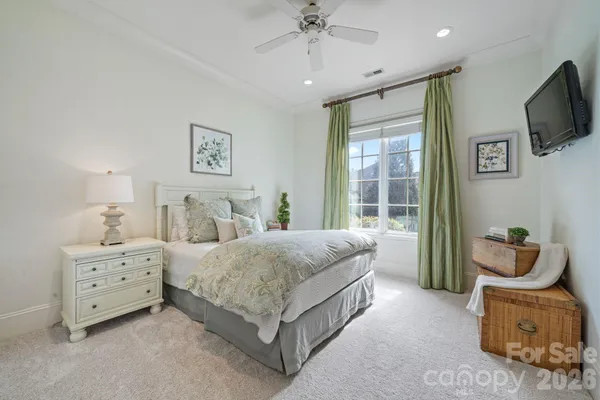 a spacious bedroom with a bed and a flat tv screen on dresser