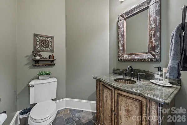 a bathroom with a granite countertop toilet sink and mirror