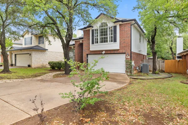 a front view of a house with a yard and large tree