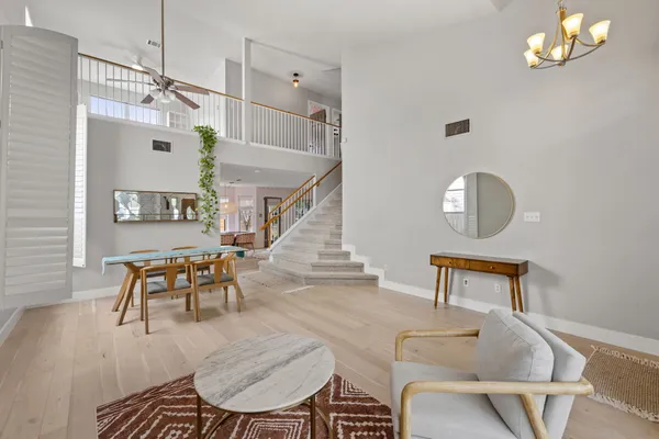a dining room with wooden floor a chandelier a wooden table and chairs
