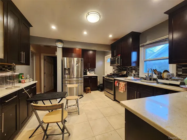 a kitchen with stainless steel appliances kitchen island granite countertop a sink stove and refrigerator