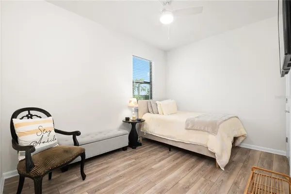 a bedroom with a bed chair and wooden floor