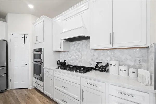 a kitchen with white cabinets and stainless steel appliances