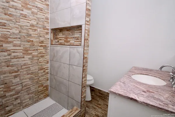 a bathroom with a granite countertop shower and a sink