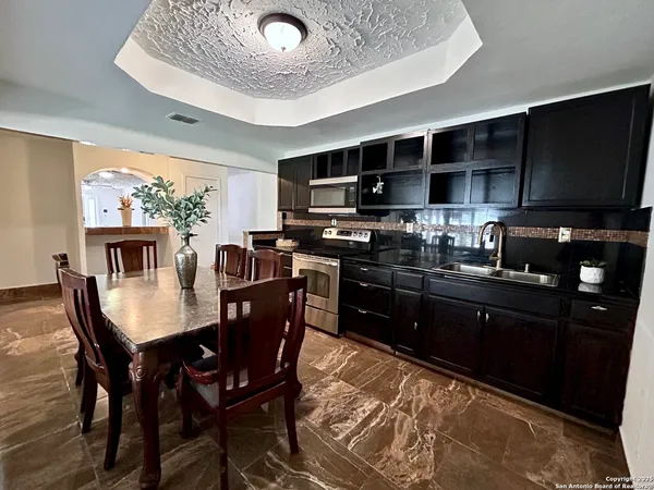 a kitchen with stainless steel appliances granite countertop a refrigerator a sink a stove a dining table and chairs