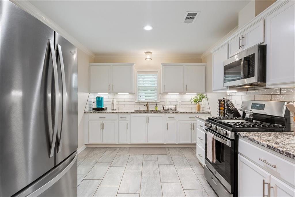 Undisclosed Address Waco, TX 76708 - Photo 12 of 30 Kitchen featuring stainless steel appliances, white cabinets, ornamental molding, light stone countertops, and decorative backsplash