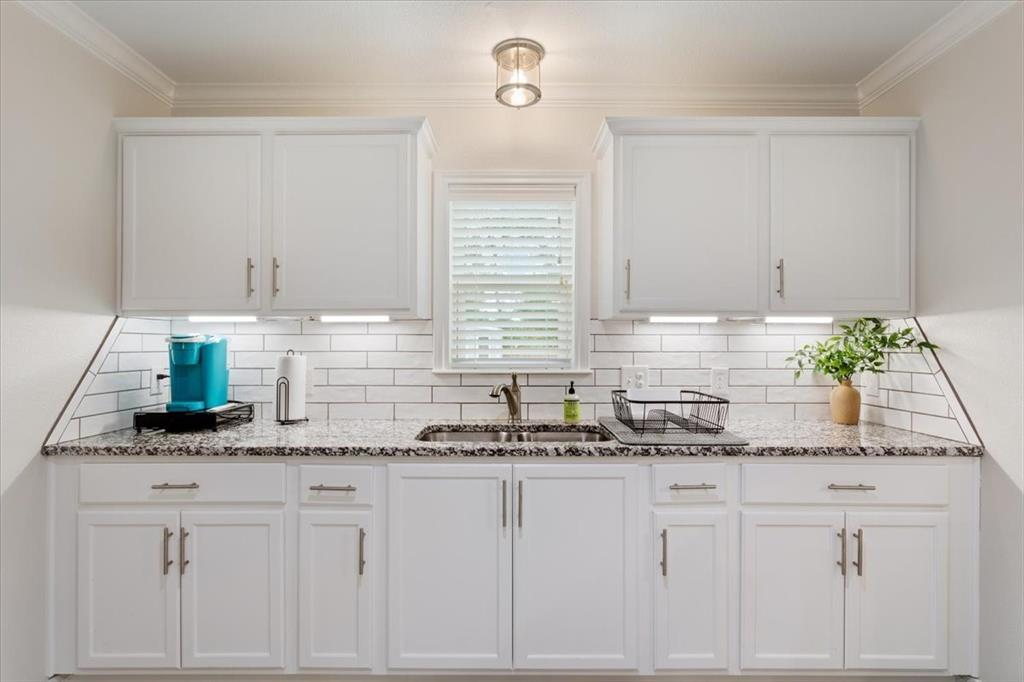 Undisclosed Address Waco, TX 76708 - Photo 13 of 30 Kitchen with white cabinetry, stone countertops, tasteful backsplash, and crown molding