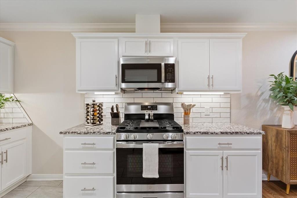 Undisclosed Address Waco, TX 76708 - Photo 14 of 30 Kitchen with stainless steel appliances, light stone counters, white cabinets, backsplash, and ornamental molding
