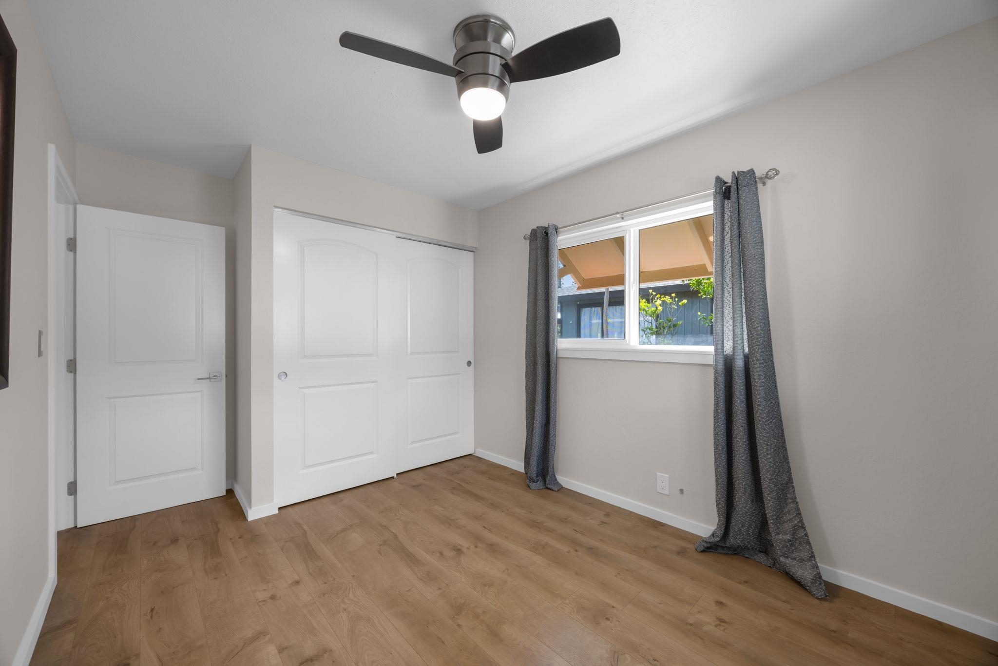 1702 Haiku Road, Unit B Haiku, HI 96708 - Photo 17 of 43 an empty room with wooden floor chandelier fan and windows