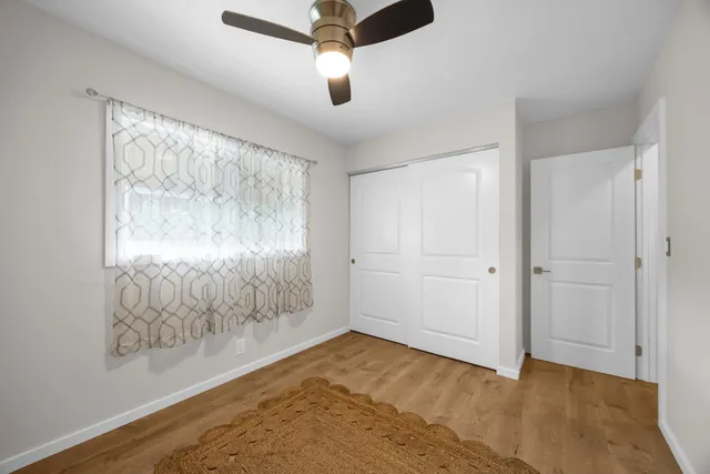 a view of empty room with wooden floor and fan