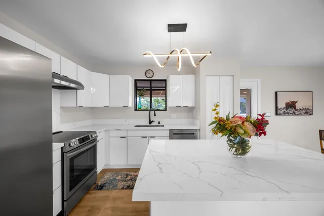 a kitchen with a stove a sink and a chandelier