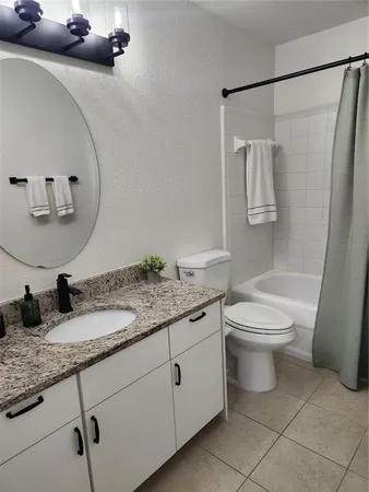 a bathroom with a granite countertop toilet sink and mirror