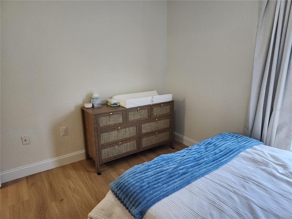 8926 Manor Loop, Unit 201B Lakewood Ranch, FL 34202 - Photo 23 of 32 a bedroom with a bed and wooden floor