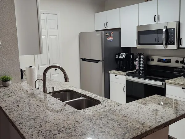 a kitchen with stainless steel appliances granite countertop a sink dishwasher a refrigerator and a stove