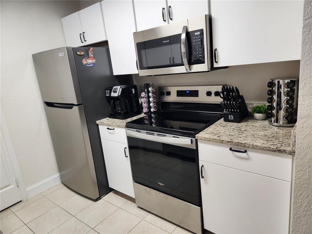 8926 Manor Loop, Unit 201B Lakewood Ranch, FL 34202 - Photo 8 of 32 a kitchen with stainless steel appliances granite countertop a refrigerator a stove and a sink