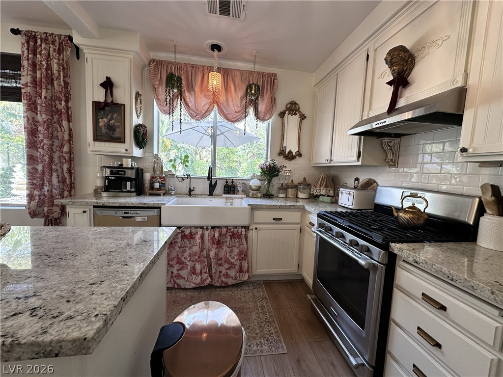 9724 Trail Rider Drive Las Vegas, NV 89117 - Photo 21 of 52 Kitchen featuring stainless steel appliances, light stone countertops, dark wood-style flooring, backsplash, and white cabinetry