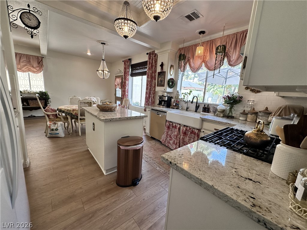 9724 Trail Rider Drive Las Vegas, NV 89117 - Photo 24 of 52 Kitchen featuring light stone countertops, beamed ceiling, light wood finished floors, white cabinetry, and a kitchen island