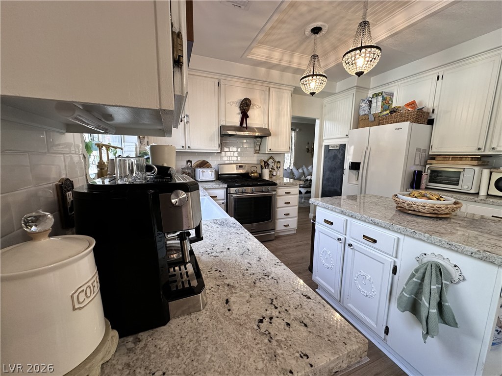 9724 Trail Rider Drive Las Vegas, NV 89117 - Photo 25 of 52 Kitchen featuring white cabinetry, gas stove, white fridge with ice dispenser, a raised ceiling, and dark wood-style flooring