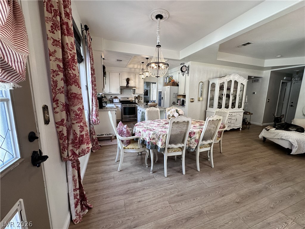 9724 Trail Rider Drive Las Vegas, NV 89117 - Photo 30 of 52 Dining room with hanging lights, light wood finished floors, and a tray ceiling