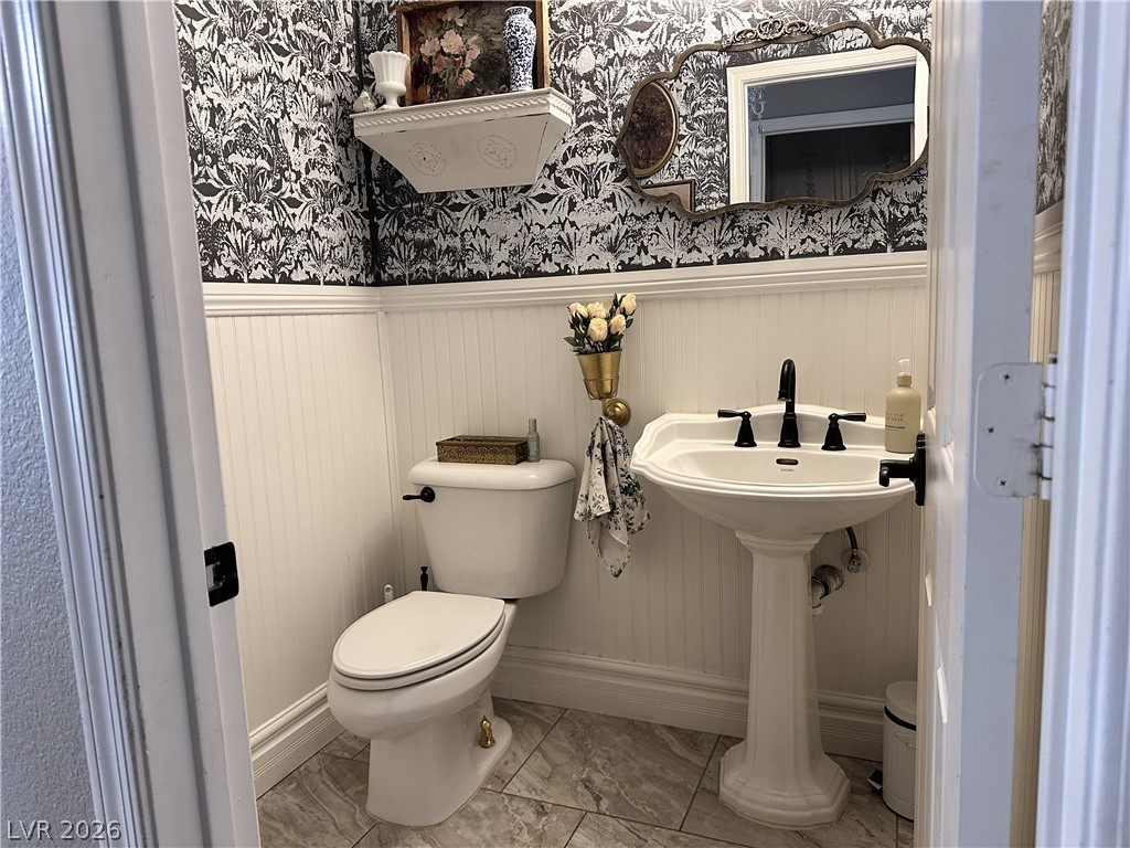 9724 Trail Rider Drive Las Vegas, NV 89117 - Photo 35 of 52 Half bathroom with wainscoting, wallpapered walls, and light marble finish flooring