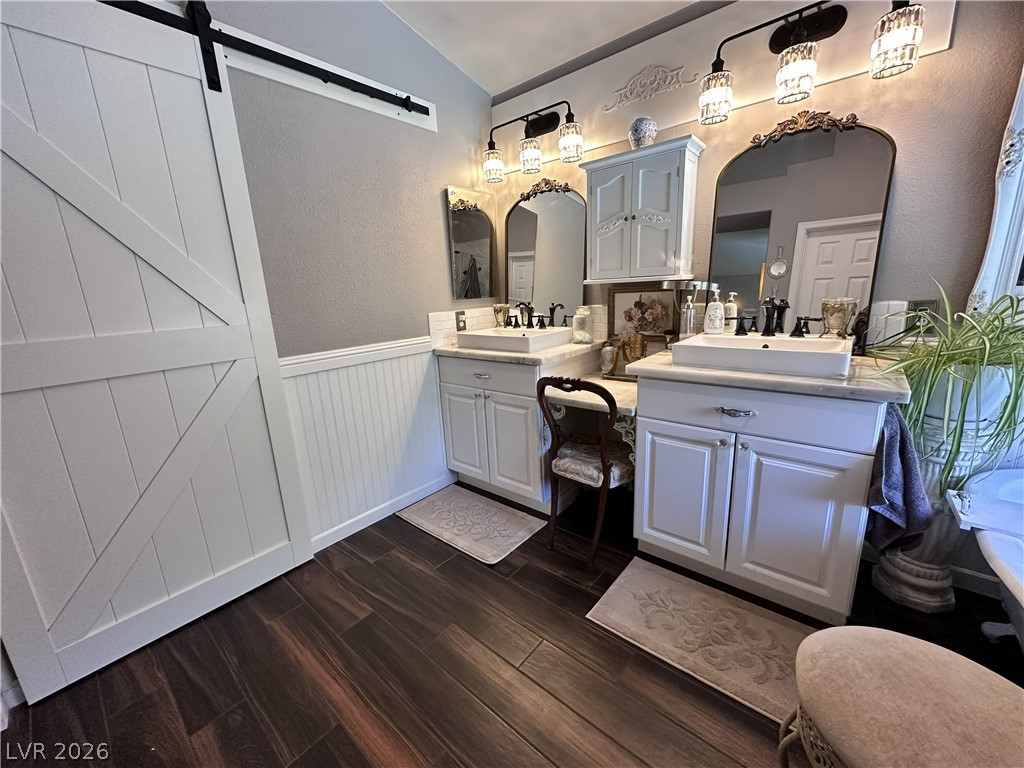 9724 Trail Rider Drive Las Vegas, NV 89117 - Photo 41 of 52 Full bathroom with lofted ceiling, two vanities, dark wood-style flooring, a wainscoted wall, and a textured wall