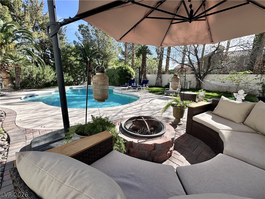 9724 Trail Rider Drive Las Vegas, NV 89117 - Photo 10 of 52 View of swimming pool featuring an outdoor living space with a fire pit, patio surround, and a fenced backyard