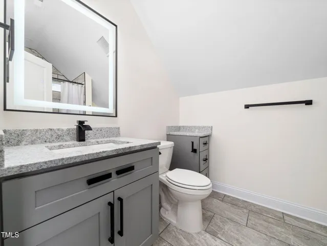 a bathroom with a granite countertop toilet sink and mirror