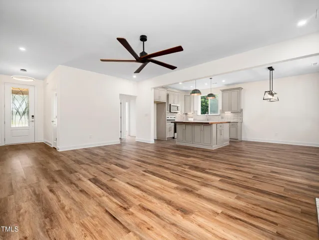 a view of a livingroom with a ceiling fan wooden floor and window