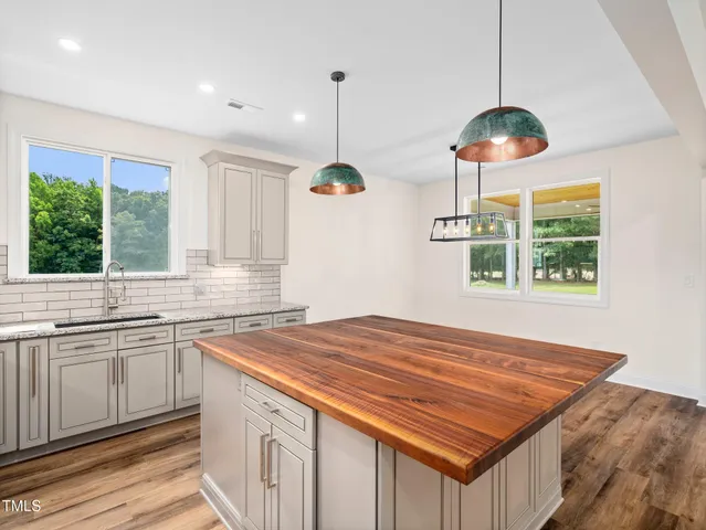 a kitchen with a stove a sink a window and cabinets