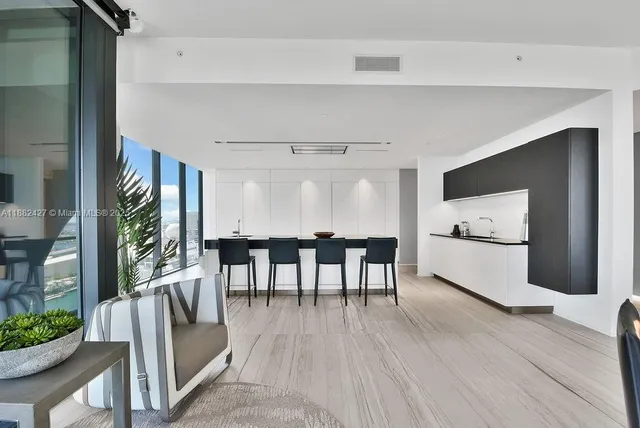 a kitchen with granite countertop a table chairs stove and white cabinets