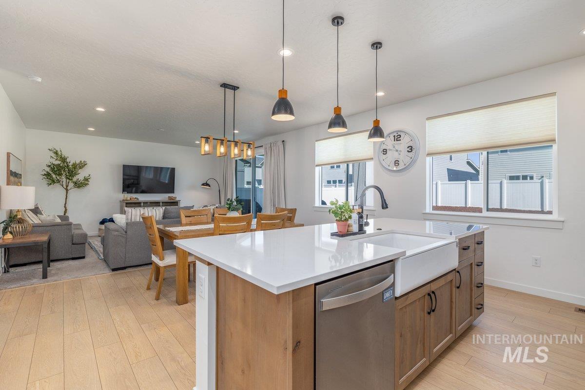 1380 West Chilitna Street Meridian, ID 83642 - Photo 13 of 50 Open-concept living area featuring light wood-finish flooring, a kitchen island with a farmhouse sink and light-toned countertop, and recessed lighting