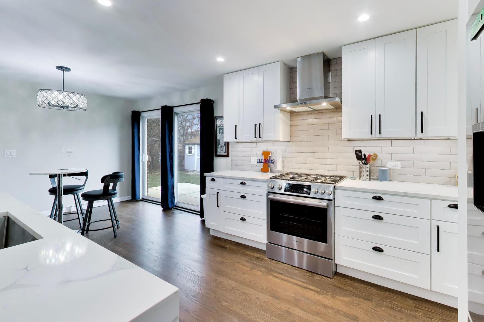 108 West Sunset Road Mount Prospect, IL 60056 - Photo 8 of 40 a kitchen with stainless steel appliances a stove a sink dishwasher a refrigerator and white cabinets with wooden floor